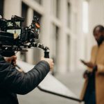 Cinematic scene of a filmmaker using camera rig outdoors, capturing a stylish male subject.