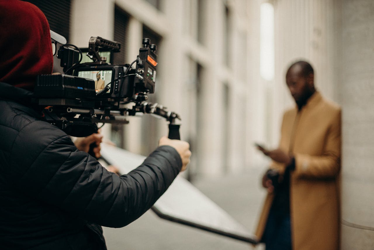 Cinematic scene of a filmmaker using camera rig outdoors, capturing a stylish male subject.
